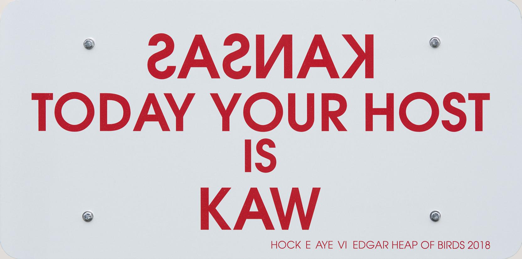 White sign with red text that reads Kansas backwards at the top and Kaw forwards at the bottom