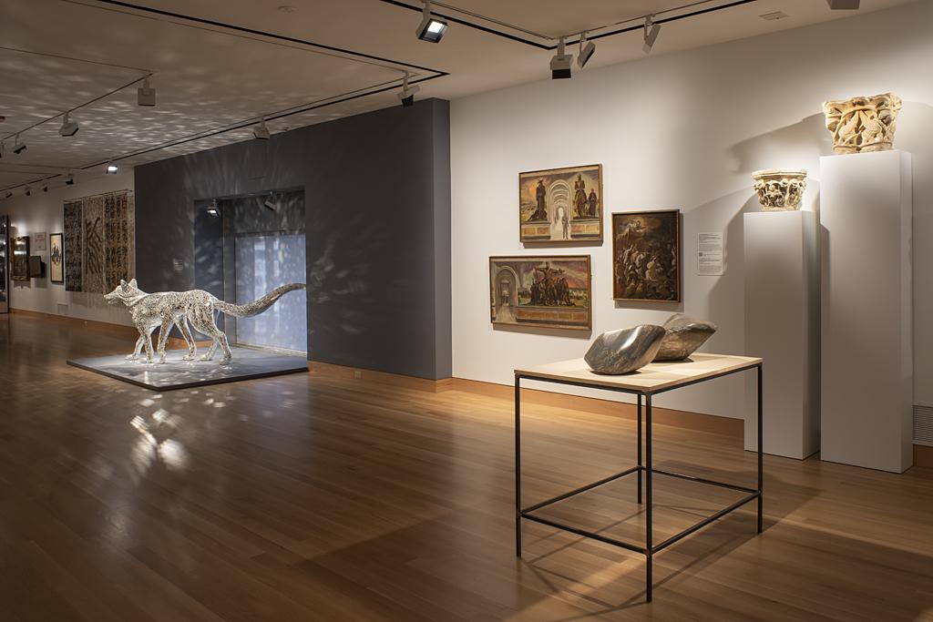 Image of a gallery space with a sparkly wolf sculpture on the floor and various works hung on the wall