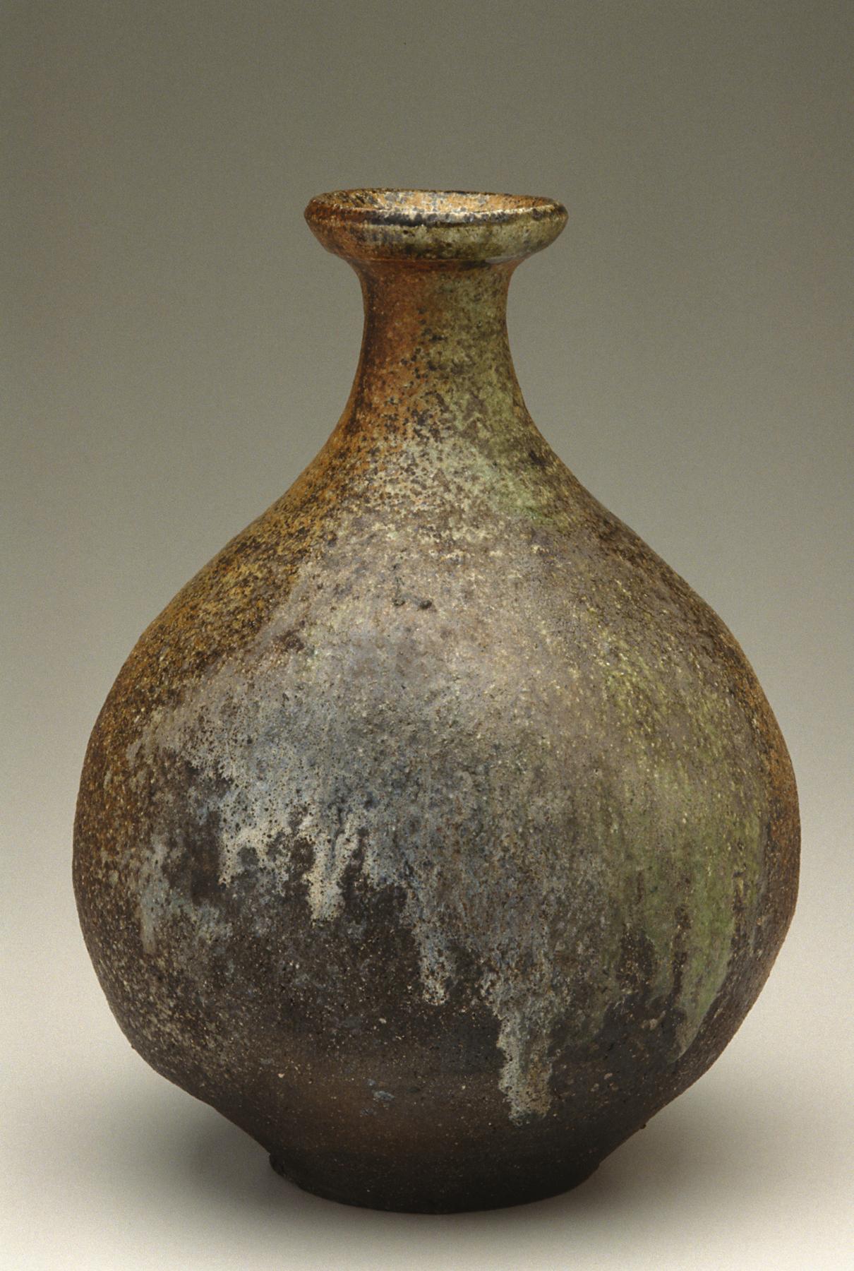 Vase with a rounded body, slender neck, and flared lip, featuring a variegated glaze in black, green, brown, and white