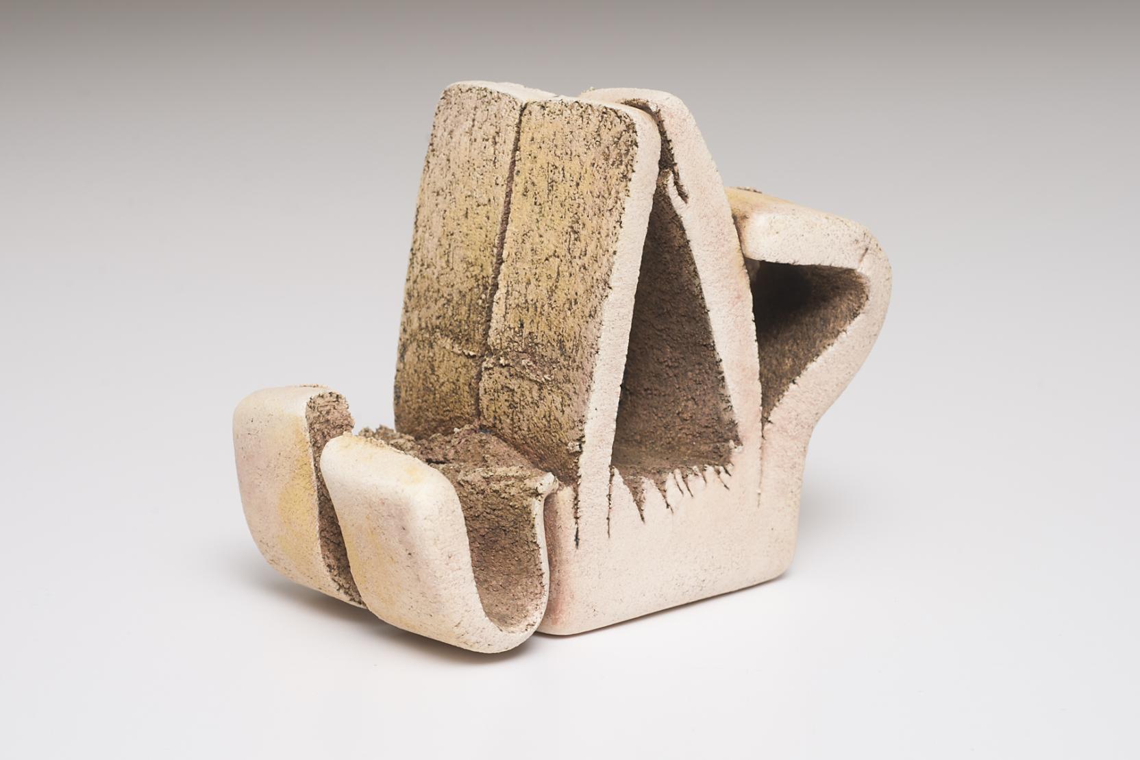 Unglazed abstract sculpture with a triangular body, a folded handle on one side, and a U-shaped element on the other